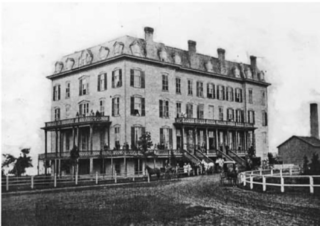 The Hyde Park House hotel in the 1870s, a tall clapboard block under a mansard roof with tiers of verandahs, carriages drawn up on the dirt road in front